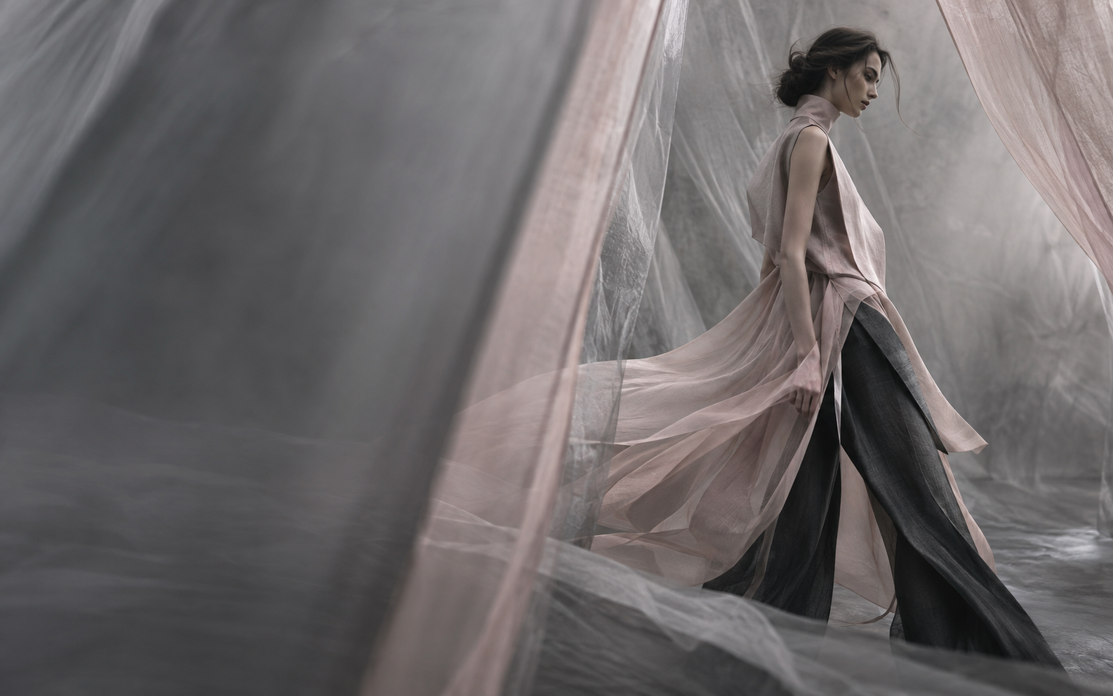 Editorial fashion figure moving through translucent fabric